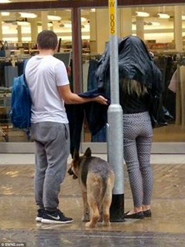 The pictures were taken in Dover and shows the man take off his jacket to shelter the shivering animal, while its owner shopped in Marks and Spencer