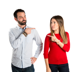 Couple Pointing Each Other Over White Background