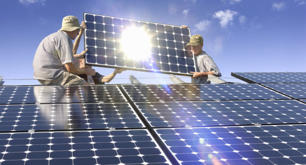 Men installing solar photovoltaic panels at sunset