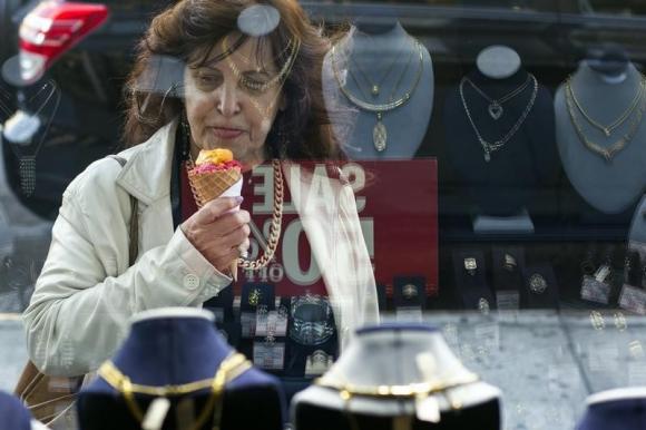 A woman eats ice cream as she looks at the display in the window of a Gold Standard jewellery store that specializes in purchasing raw gold and silver in New York April 15, 2013.     REUTERS/Lucas Jackson