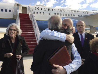 CLICK IMAGE for slideshow: Alan Gross embraces Tim Rieser (C, back to camera), a member of Senator Patrick Leahy's office, on the tarmac as he disembarks from a U.S. government plane with wife Judy (L) at Joint Base Andrews in Maryland outside Washington December 17, 2014 in this photo courtesy of Jill Zuckman. The United States plans to restore diplomatic relations with Cuba more than 50 years after they were severed, a major policy shift after decades of hostile ties with the communist-ruled island, President Barack Obama said on Wednesday. Obama discussed the changes with Cuban President Raul Castro on Tuesday in a telephone call that lasted nearly an hour. Castro spoke in Cuba as Obama made his announcement on a policy shift made possible by the release of American Alan Gross, 65, who had been imprisoned in Cuba for five years. REUTERS/Jill Zuckman/Gross Family spokesperson/Handout via Reuters (UNITED STATES - Tags: POLITICS) ATTENTION EDITORS - THIS PICTURE WAS PROVIDED BY A THIRD PARTY. REUTERS IS UNABLE TO INDEPENDENTLY VERIFY THE AUTHENTICITY, CONTENT, LOCATION OR DATE OF THIS IMAGE. FOR EDITORIAL USE ONLY. NOT FOR SALE FOR MARKETING OR ADVERTISING CAMPAIGNS. NO SALES. NO ARCHIVES. THIS PICTURE WAS PROCESSED BY REUTERS TO ENHANCE QUALITY. AN UNPROCESSED VERSION WILL BE PROVIDED SEPARATELY