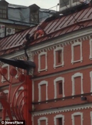 The man can be seen bravely scaling the building in an attempt to get to the dog and rescue it from the huge drop
