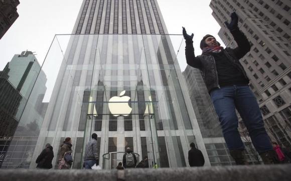 A man poses for a photo in front of the Apple store on 5th Avenue in New York, December 26, 2013.  REUTERS/Carlo Allegri