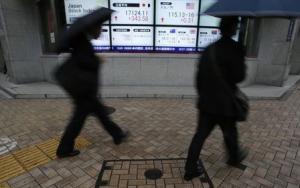 Pedestrians with umbrellas walk past an electronic&nbsp;&hellip;