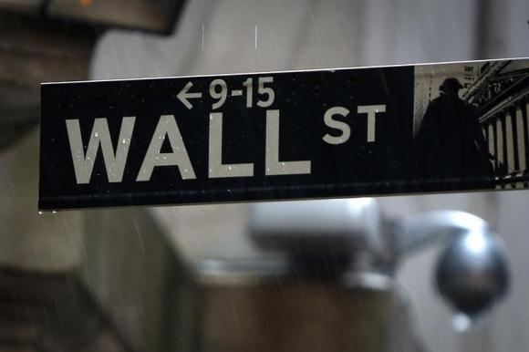 A Wall Street sign is pictured in the rain outside the New York Stock Exchange in New York June 9, 2014.  REUTERS/Carlo Allegri